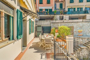A terrace with outdoor furniture, a stone wall, and potted plants. - [Sulla via dell'amore] Riomaggiore/private parking (Riomaggiore)