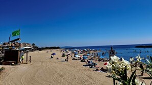 Una playa con sombrillas, gente y una estación de salvavidas.