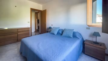 Un dormitorio con cama, mesitas de noche, armario y ventana.