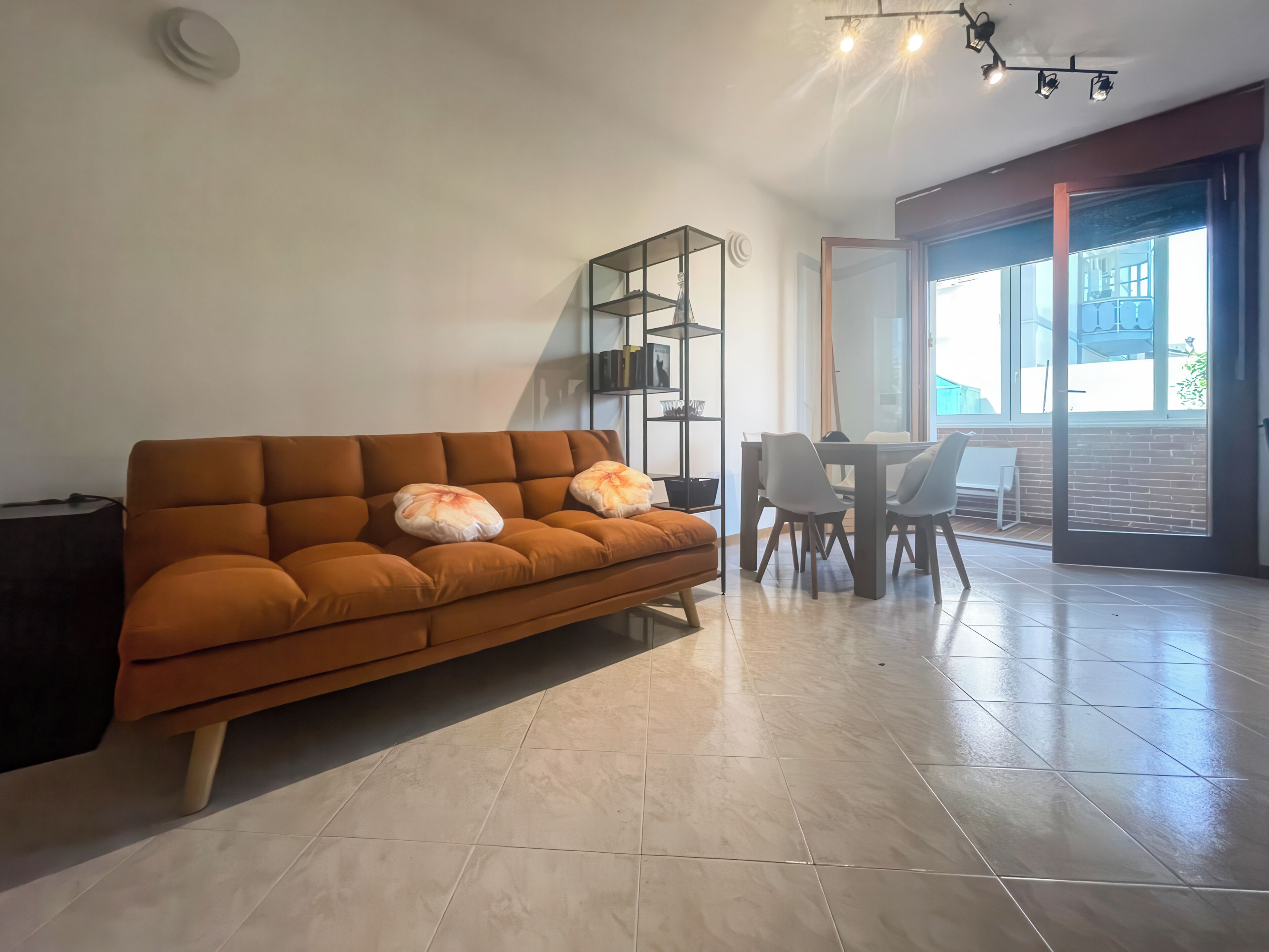 Ein modernes Wohnzimmer mit einer Couch, einem Esstisch mit Stühlen und einem großen Fenster.