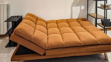 Un divano moderno con struttura in legno e seduta imbottita, posizionato su un pavimento piastrellato.