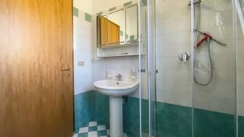 Une salle de bain avec une porte en bois, un lavabo, un miroir et une douche.