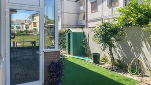 Ein Wohngebäude mit Rasen, einer kleinen Gartenhütte und einem sichtbaren Balkon.