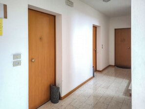 A hallway with wooden doors, a trash bin, and a light switch on the wall.