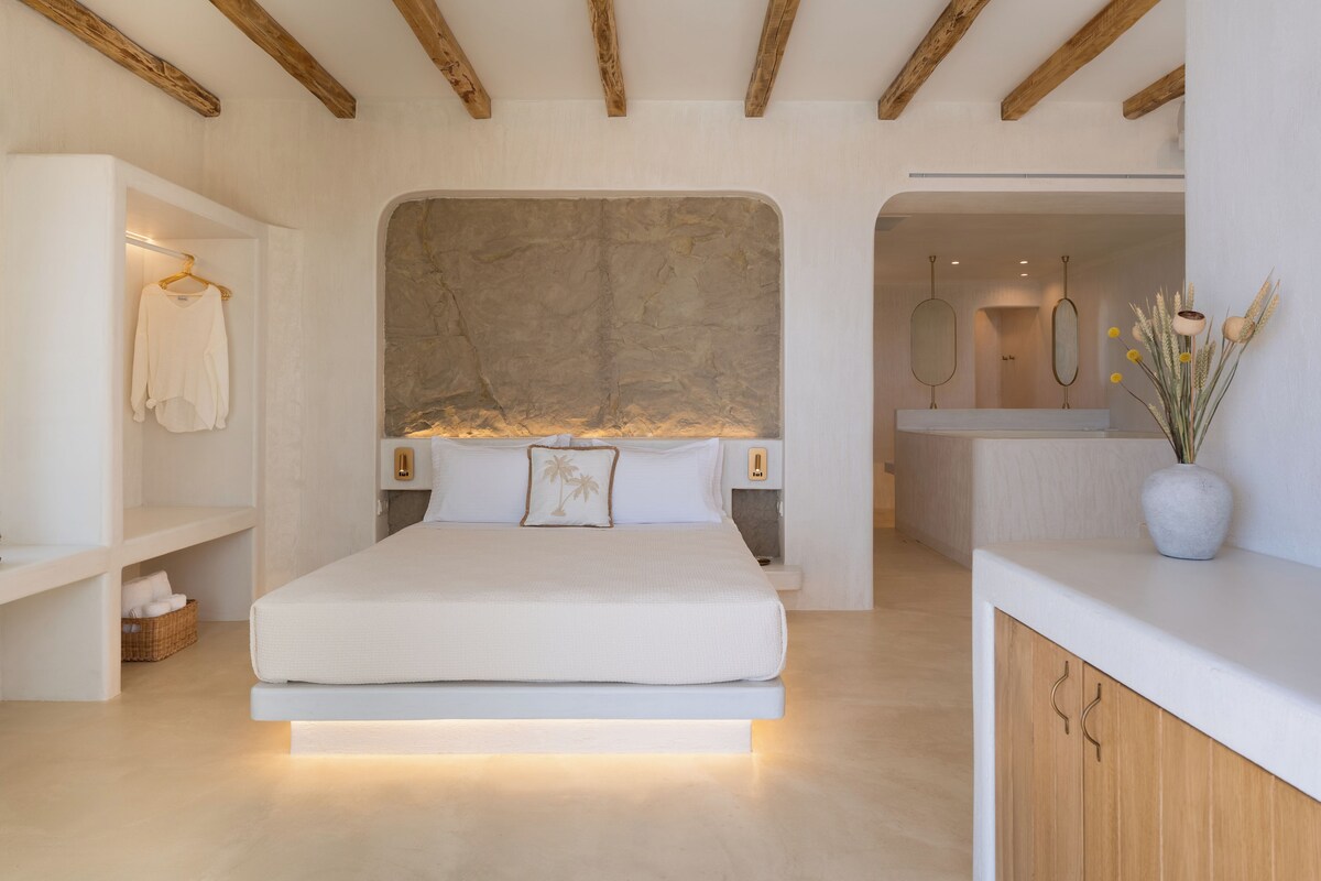 A modern bedroom with a large bed, a stone accent wall, and a minimalist design.