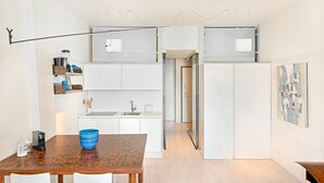 Una cucina moderna con mobili bianchi, un tavolo da pranzo in legno e una ciotola blu.