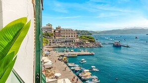 Una cittadina costiera con un porto turistico, imbarcazioni e un grande edificio con numerosi balconi.
