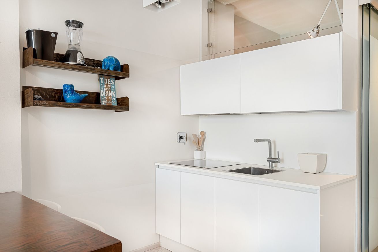 Una cucina moderna con mobili bianchi, lavello incassato e piano di lavoro.