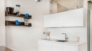 Una cucina moderna con mobili bianchi, lavello incassato e piano di lavoro.