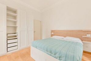 Ein Schlafzimmer mit einem Bett, einem weißen Kleiderschrank und einer Tür.