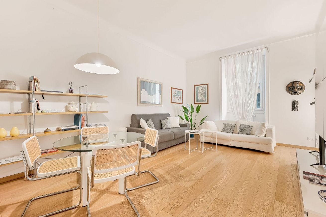 A modern living room with a glass dining table, two sofas, and a coffee table.