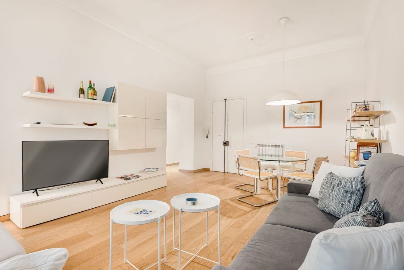 Un salon moderne comprenant un téléviseur à écran plat, un canapé, une table à manger avec des chaises et une petite table basse.