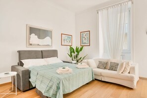 A modern bedroom with a bed, a sofa, a small table, and artwork on the walls. - [Atto primo]Central area-Near the station (La Spezia)