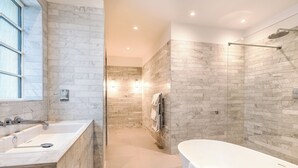 A modern bathroom with a marble sink, a freestanding bathtub, and a shower area with a glass door. - Fields in Frame at No. 64 (London)