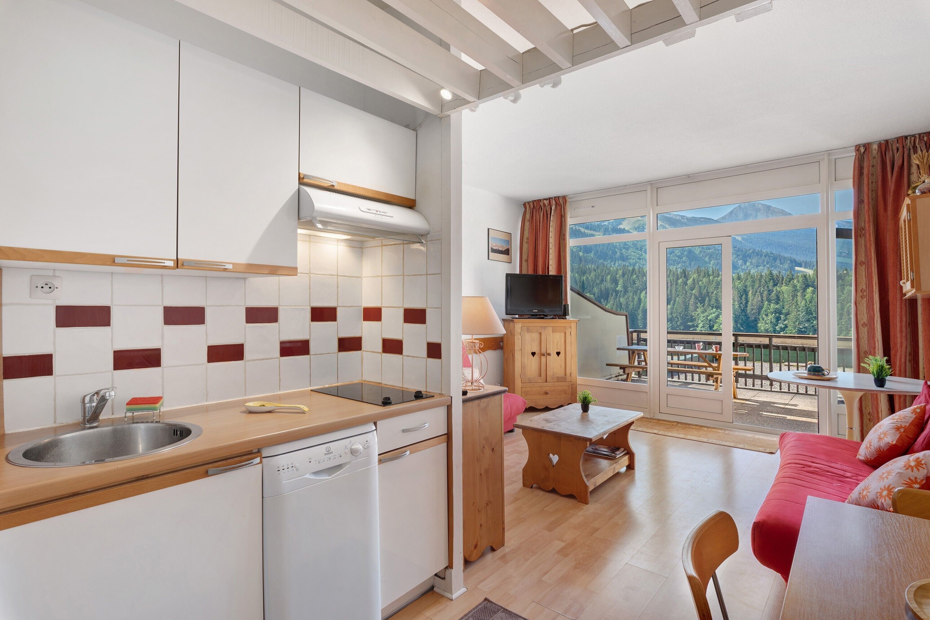Een moderne keuken met een ingebouwde vaatwasser, een eethoek met een tafel en stoelen, en een groot raam met uitzicht op de bergen.