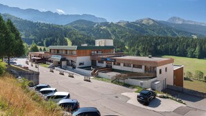 A modern building with a ski resort sign, parking area, and a view of mountains. - Superb Mountain View Apartment at the Foot of the Slopes with Large Private Terrace (Villard-de-Lans)