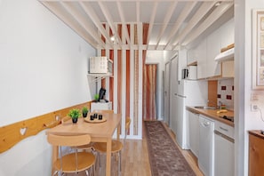 A compact kitchen with a dining area, featuring a microwave, coffee maker, and a sink.