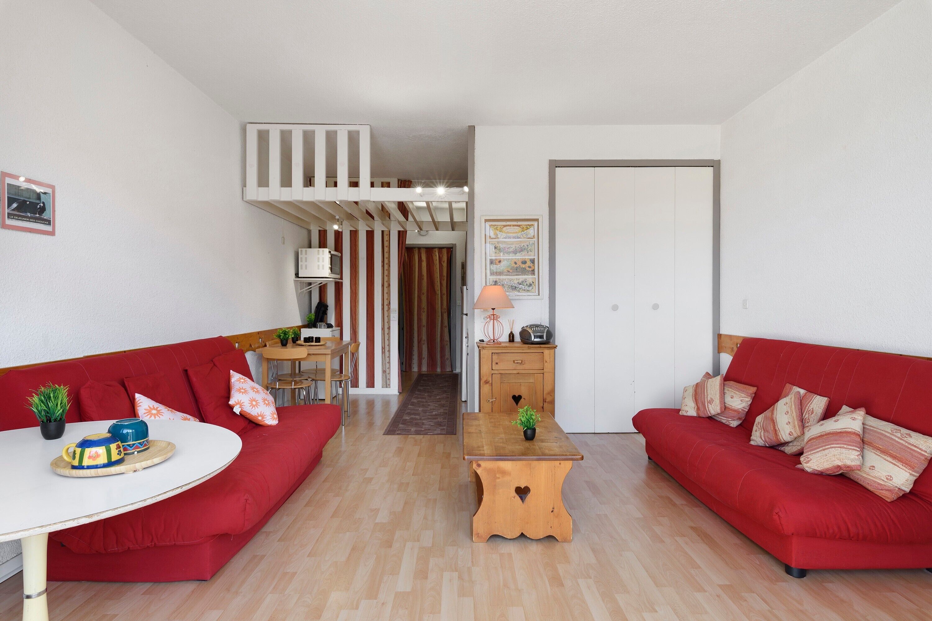 Una sala moderna con sofás rojos, una mesa de centro de madera y una zona de comedor con una mesa y sillas.