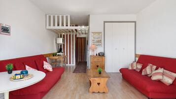 Una sala moderna con sofás rojos, una mesa de centro de madera y una zona de comedor con una mesa y sillas.