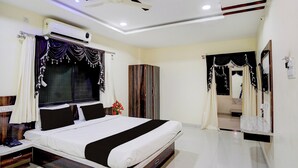 A hotel room with a bed, a wardrobe, a vanity with a mirror, and a ceiling fan. - Super Collection O Daulatabad Fort (Chhatrapati Sambhajinagar)