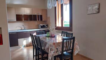 Un espace repas avec une table recouverte d’une nappe à motifs, entourée de chaises.