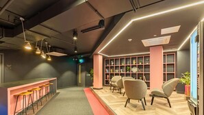 A modern interior with a bar area, seating, and a bookshelf. - Student Only Crown House (Brighton and Hove)