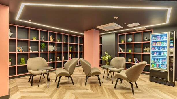A modern lounge area with seating, bookshelves, and a vending machine. - Student Only Crown House (Brighton and Hove)