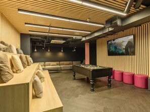 Ein stilvoller Aufenthaltsbereich mit Billardtisch, Sofas und Fernseher.
