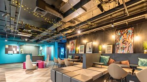 A modern office space with a herringbone wood floor, modular seating, and a variety of wall art. - Student Only Crown House (Brighton and Hove)