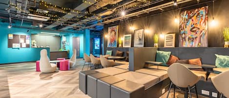 A modern office space with a herringbone wood floor, modular seating, and a variety of wall art.
