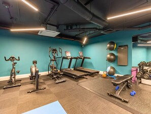 Ein Fitnessraum mit Laufbändern, Crosstrainern, Rudergeräten, Kurzhanteln und Fitnessbällen.