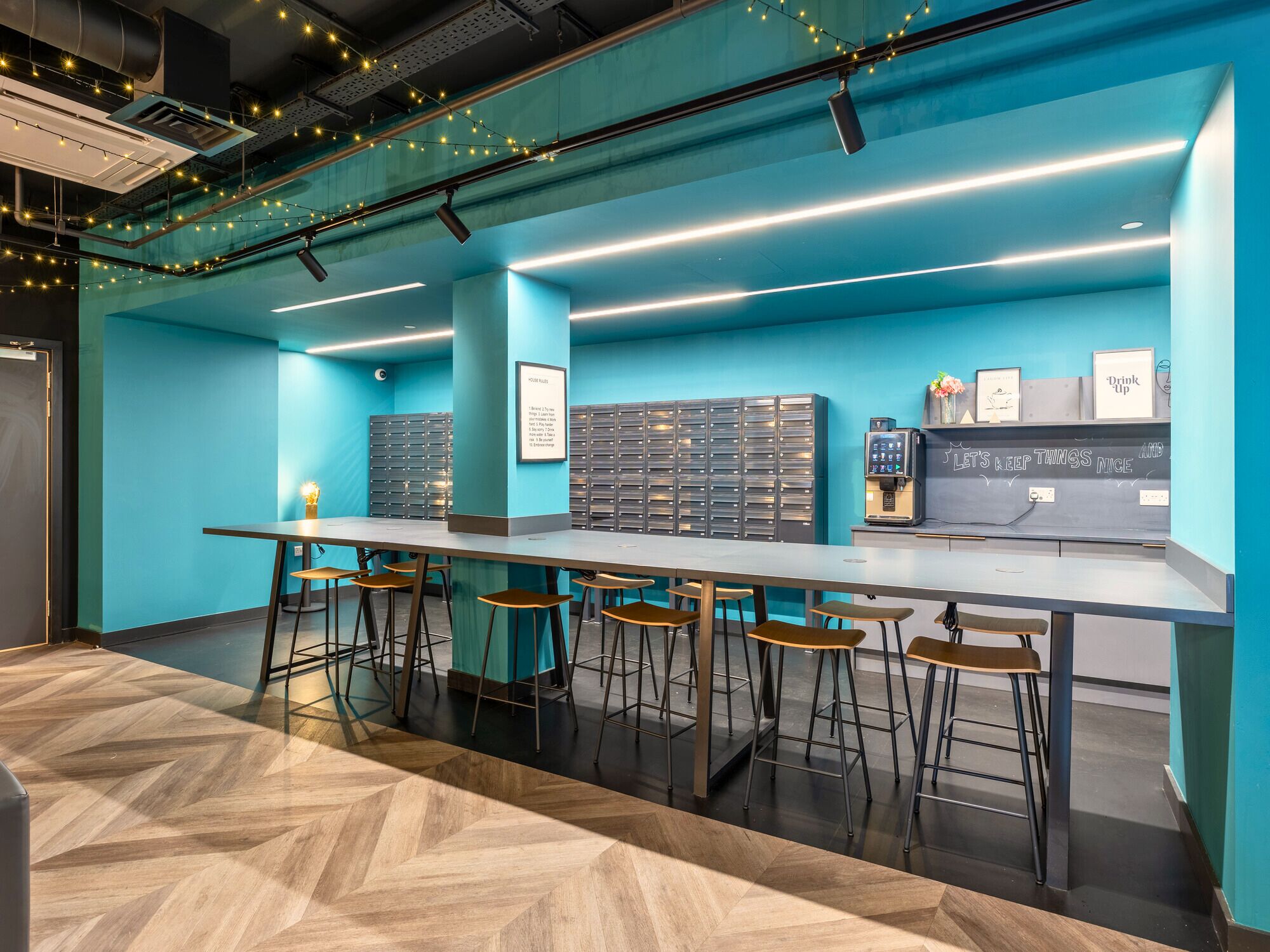 A modern bar area with a long counter, multiple stools, and a wall-mounted cash register.