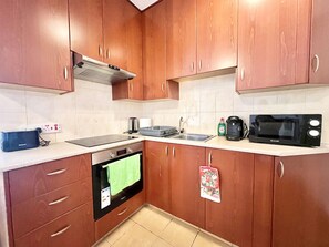 Eine Küche mit Holzschränken, einer Mikrowelle, einem Wasserkocher und einem Toaster.