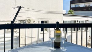 En balkong med ett bord, en flaska vin och ett glas.