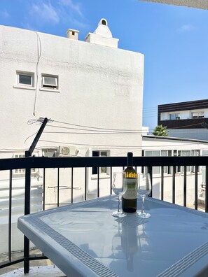 Ein Balkon mit Tisch, einer Weinflasche und einem Glas.