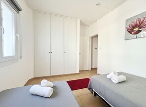 Une chambre d’hôtel avec deux lits, un tapis rouge, un tableau et une armoire.