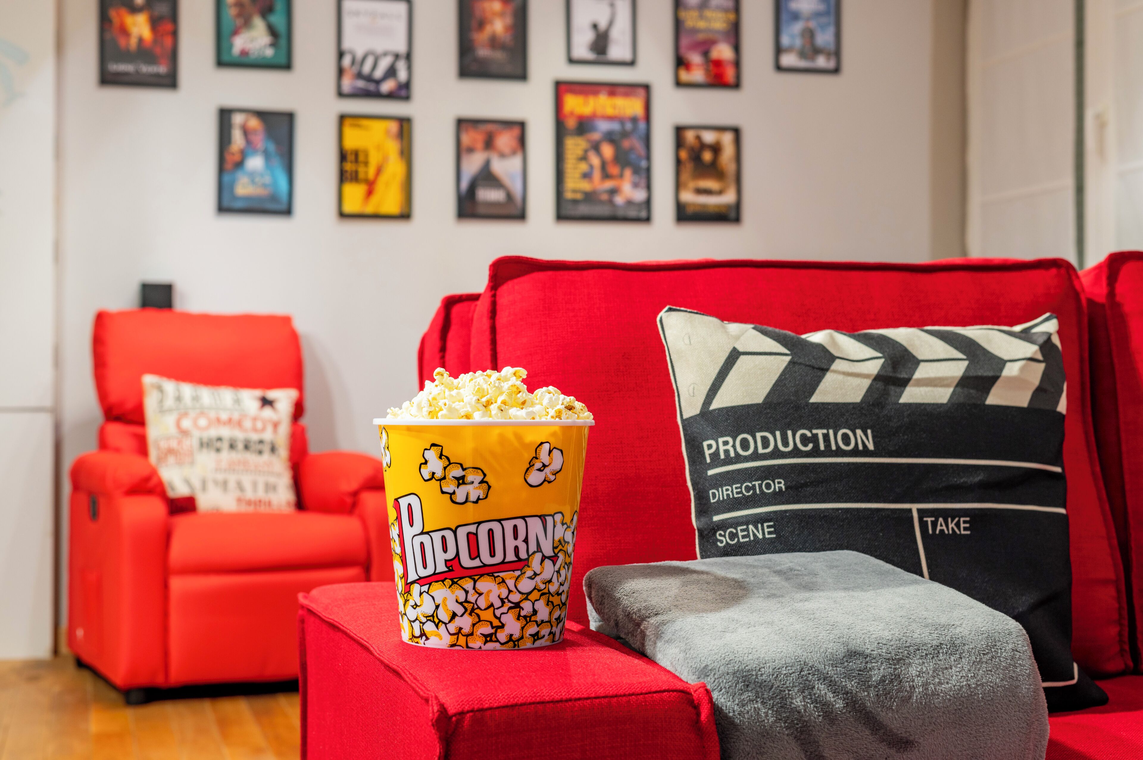 A red couch with a popcorn bucket and a clapperboard pillow.