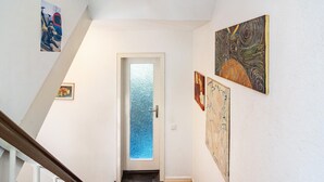 A hallway with a door leading to a room, decorated with various artworks on the walls.