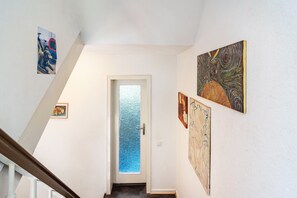 A hallway with a door leading to a room, decorated with various artworks on the walls.