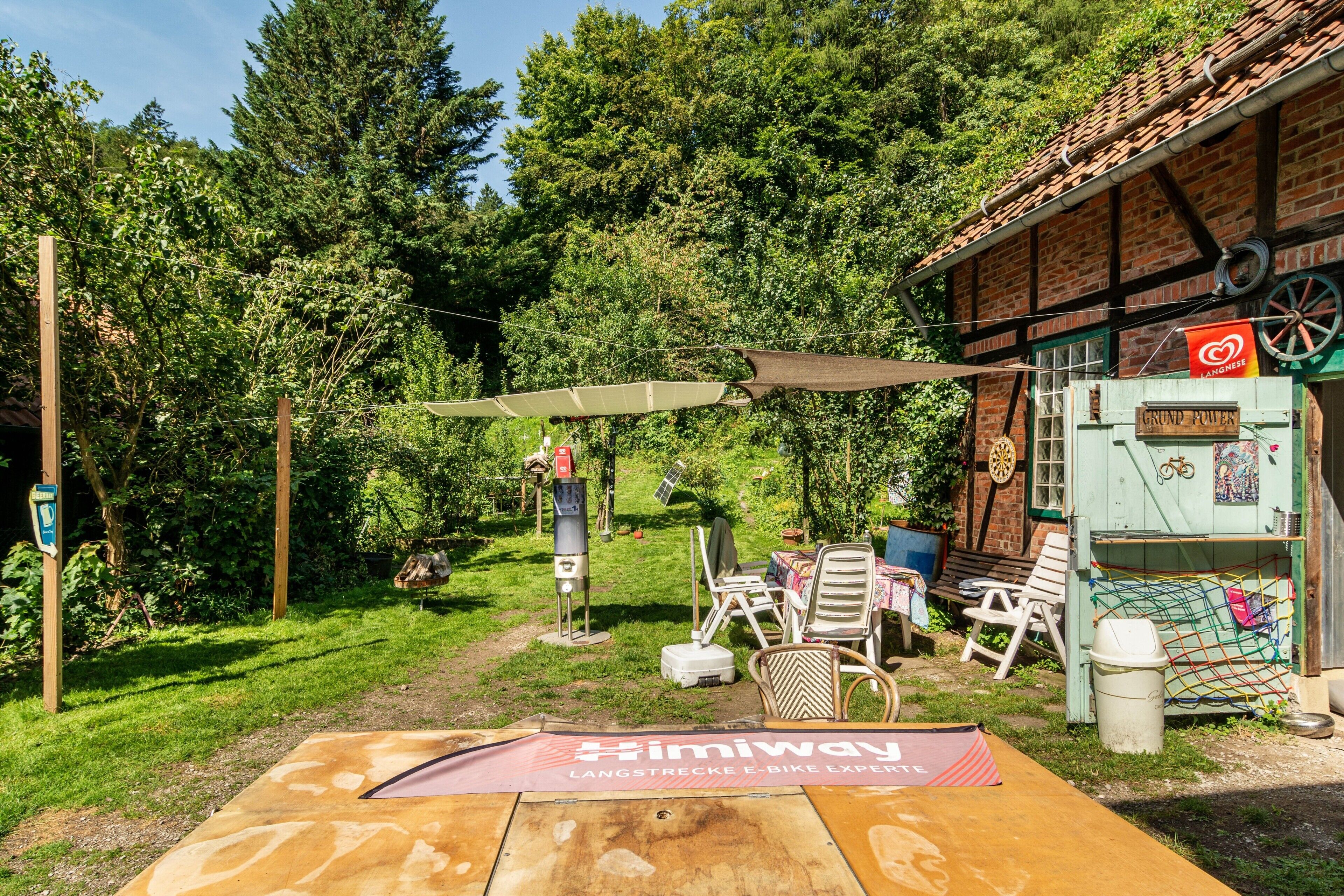 A garden area with a table, chairs, and a sign for 'Skimway Langstrecke E-Bike Experience'.