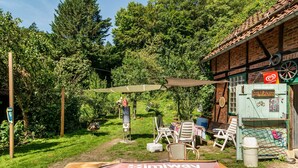 A garden area with a table, chairs, and a sign for 'Skimway Langstrecke E-Bike Experience'.