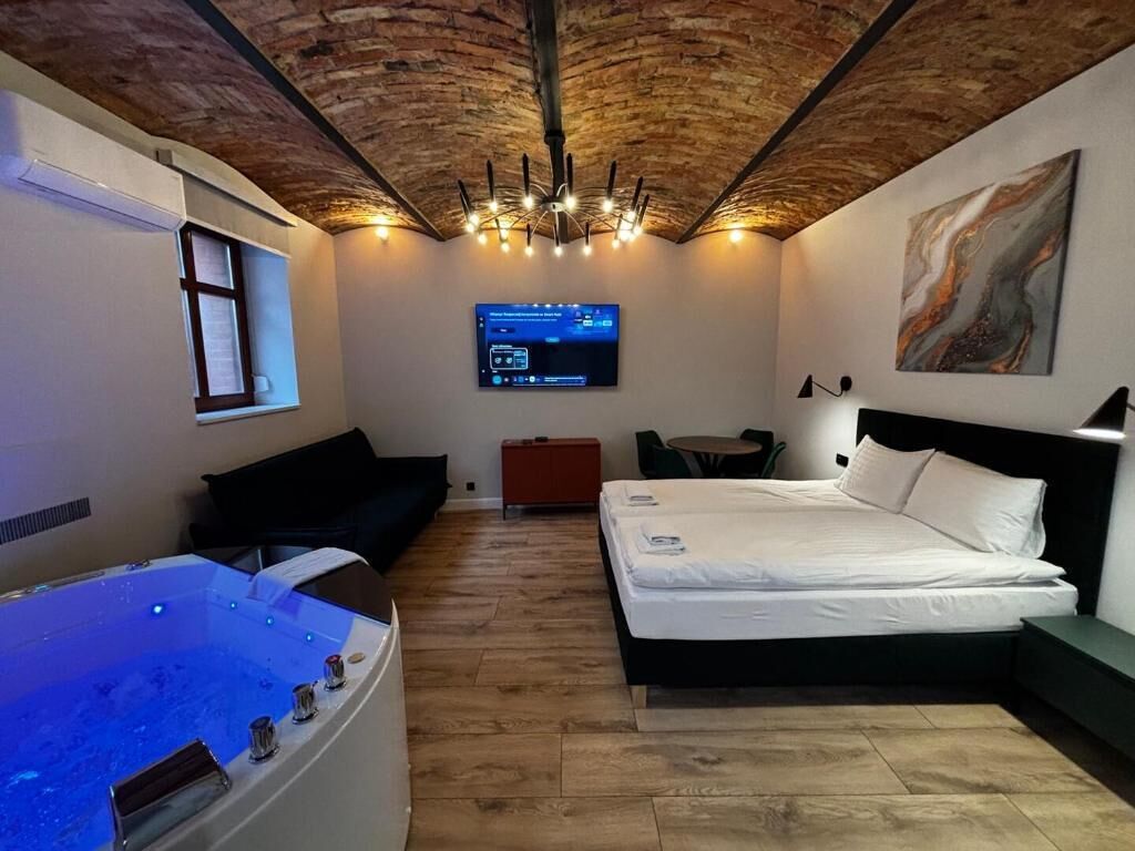A room with a bed, a massage table, a TV, and a painting on the wall.