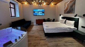 Une chambre à coucher moderne équipée d’un lit, d’un fauteuil massant, d’une télévision et d’un jacuzzi.