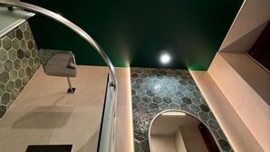 Une salle de bain moderne avec un mur d’accent vert, une baignoire et un espace douche.