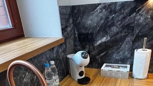 Une cuisine avec un évier noir, un robinet en cuivre et un dosseret en marbre.