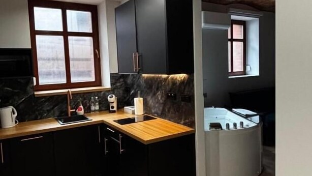 Une cuisine moderne avec des meubles de couleur sombre, un plan de travail en bois et une cuisinière intégrée.
