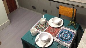 Uma cozinha compacta com pia, fogão e armários. Há uma mesa posta com pratos, copos e talheres.