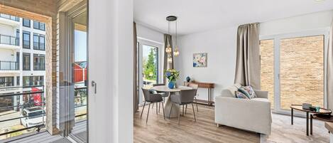 A modern apartment with a dining area, a sofa, and a view of the city.