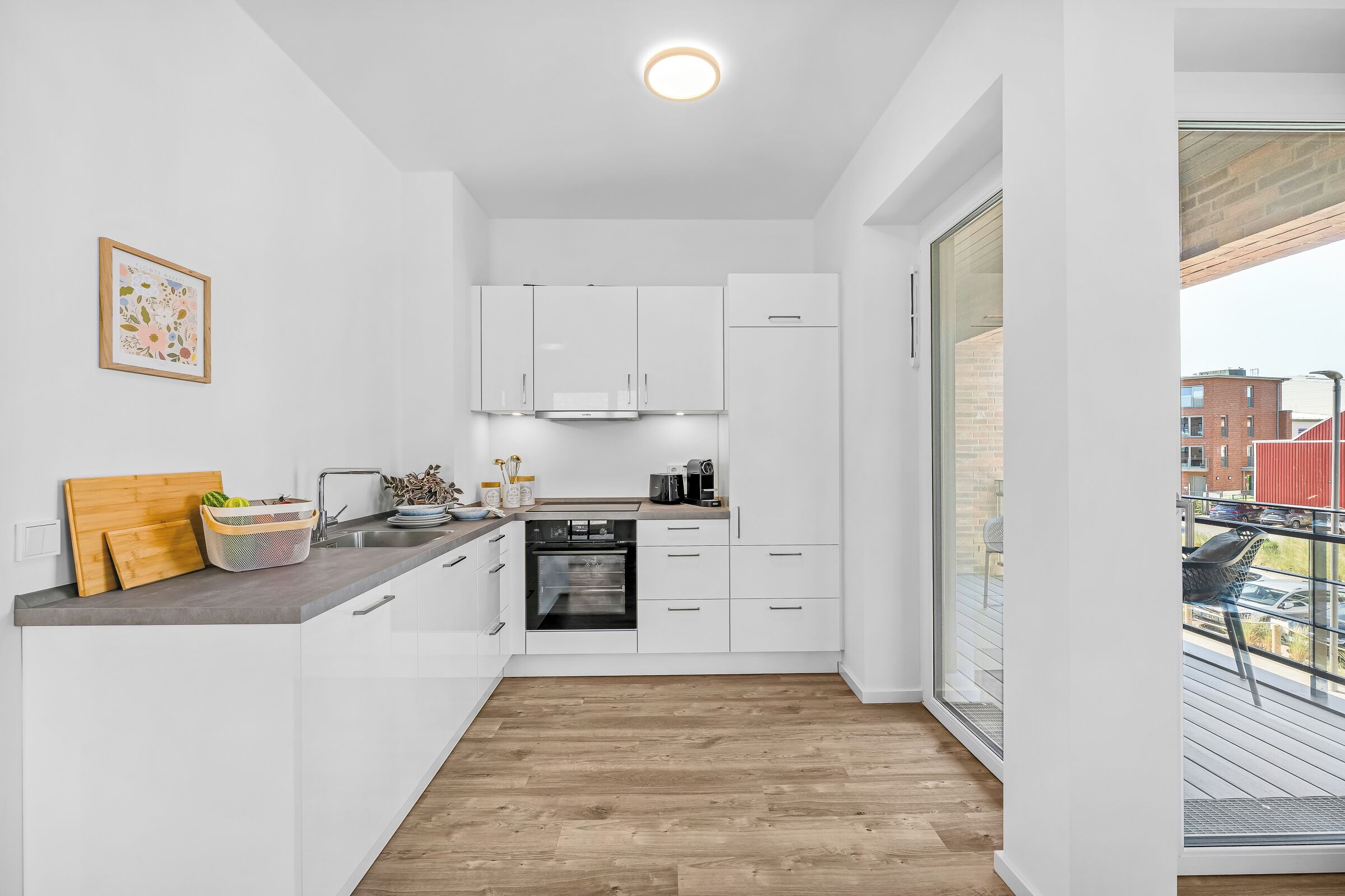 Una cocina moderna con armarios blancos, horno empotrado y encimera de madera.