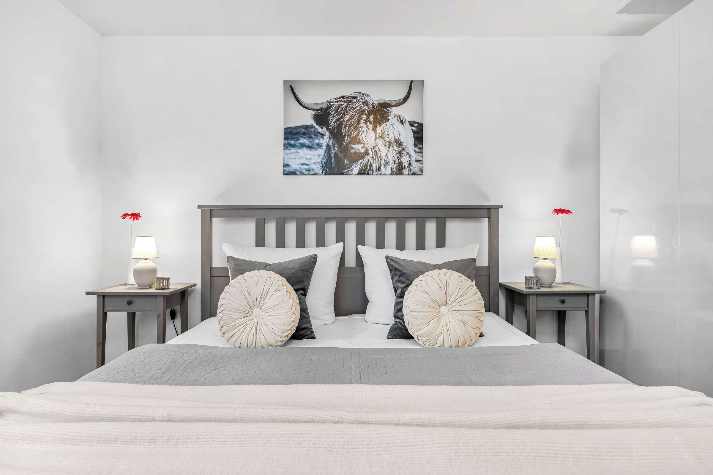 Ein Schlafzimmer mit einem Bett, zwei Nachttischen, einem Kopfteil und einem Wandbild eines Stiers.
